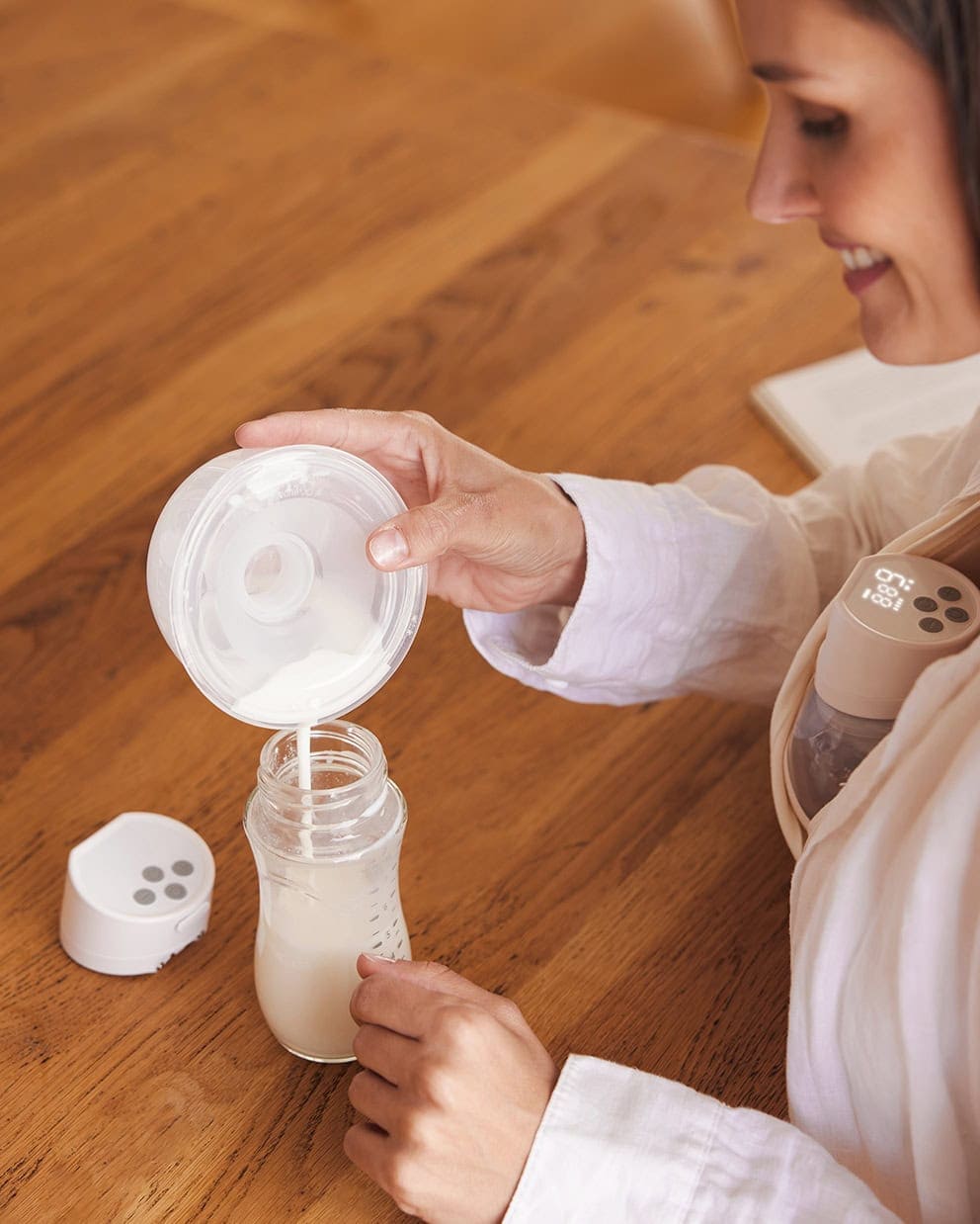 9 Women pouring milk into bottle from Momcozy S12 Pro Breast Pump